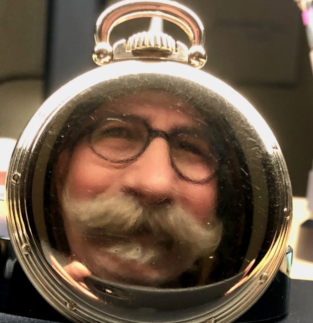 Jeff&rsquo;s face reflected in the polished case back of a pocket watch on his workbench