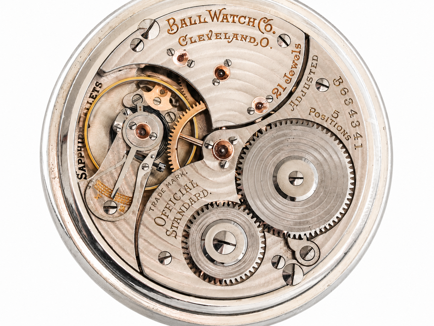 Pocket watch movement showing gears, balance wheel, and engraved metal plates with maker's markings from Cleveland, Ohio.