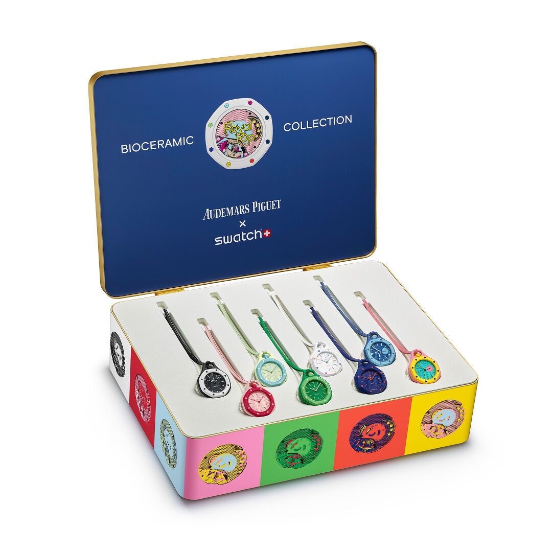 Open collector's box displaying six colorful pendant watches with ceramic dials in various colors arranged in a blue lid case with gold trim.
