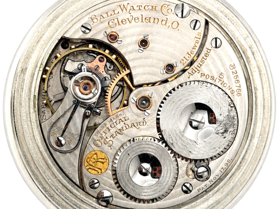 Open pocket watch movement showing jeweled escapement, gear train, and brass balance wheel with Ball Watch Co. Cleveland, O. markings.