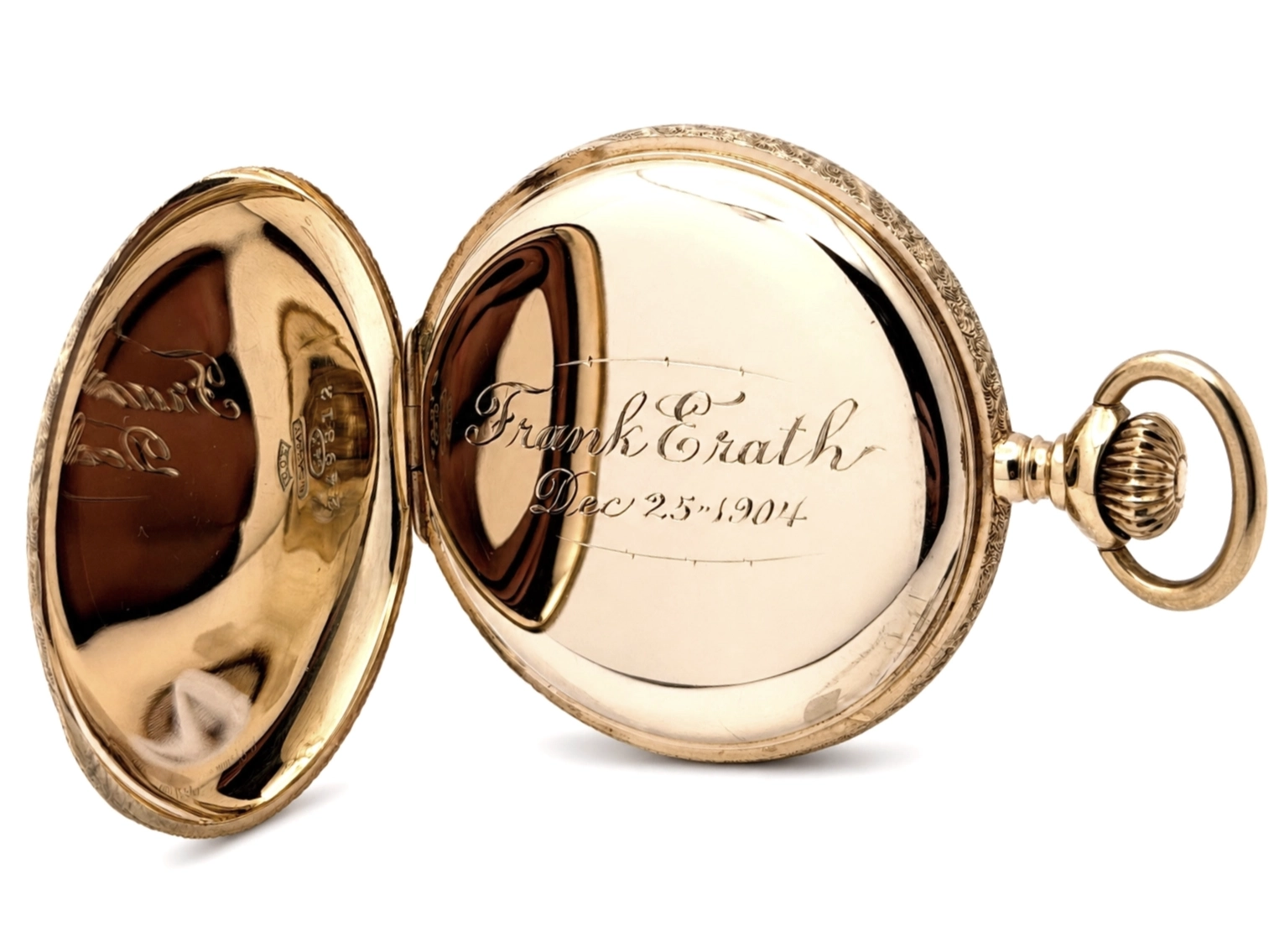 Opened gold pocket watch with engraved hunting case showing personalized inscription on inner cover.