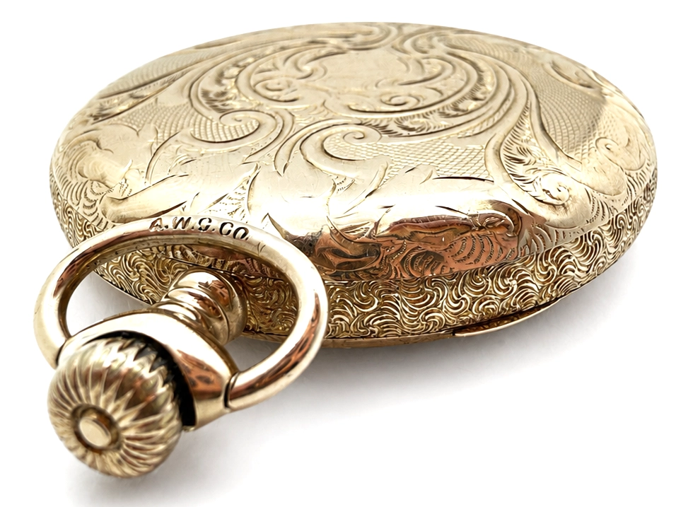 Ornate engraved pocket watch case back with decorative swirl patterns and attached bail loop.