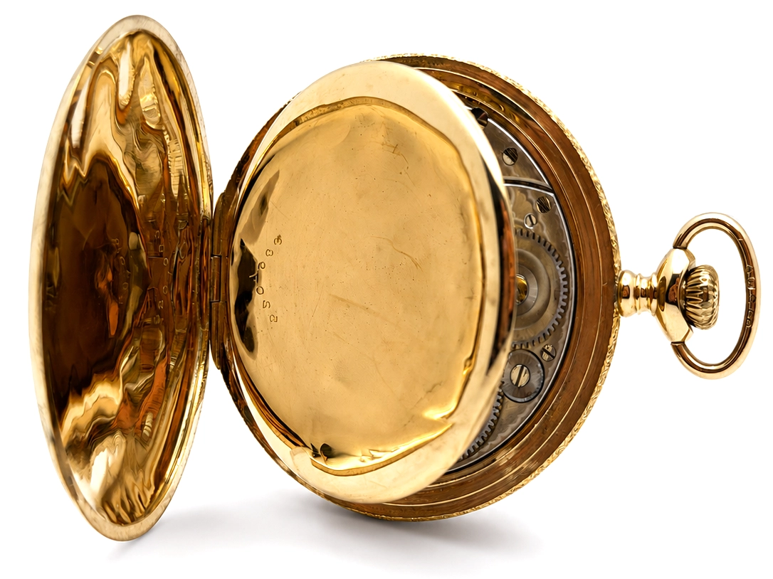 Gold pocket watch open case showing movement gears and decorated interior with polished case back.