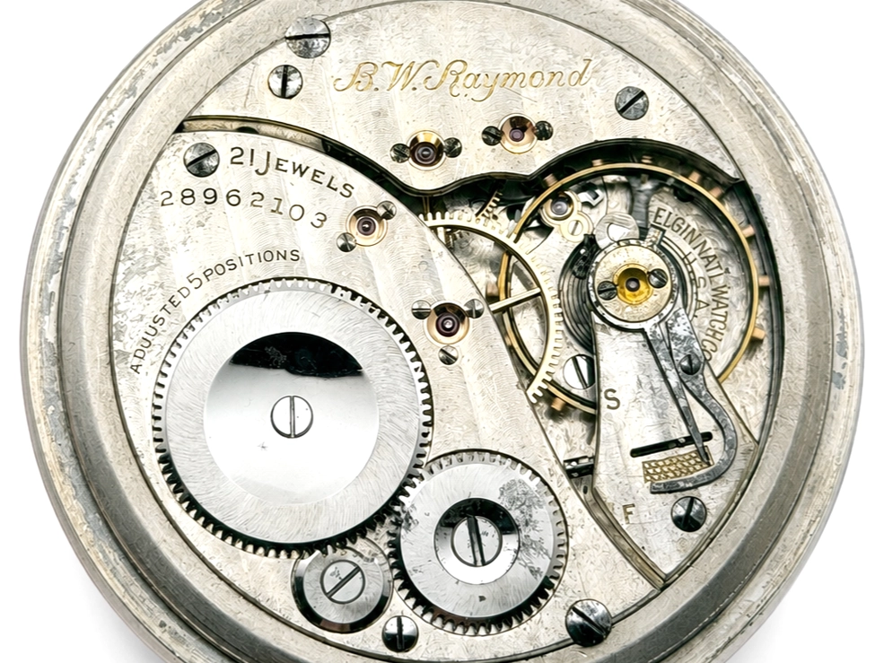 Elgin B.W. Raymond Grade 478 (1926) — open movement showing decorated balance wheel, jeweled bearings, and engraved "B.W. Raymond"…