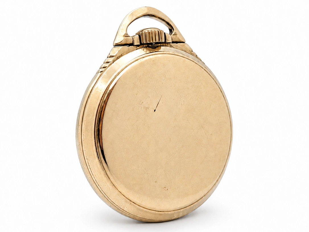 Gold pocket watch case with hinged bow and polished oval back, closed and shown from rear angle.