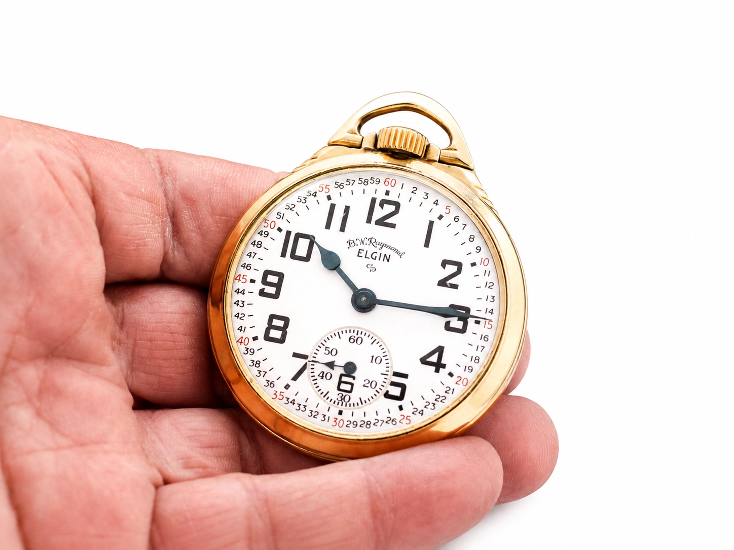 Gold-filled open-face pocket watch with white dial, bold Arabic numerals, subsidiary seconds dial, held in hand.