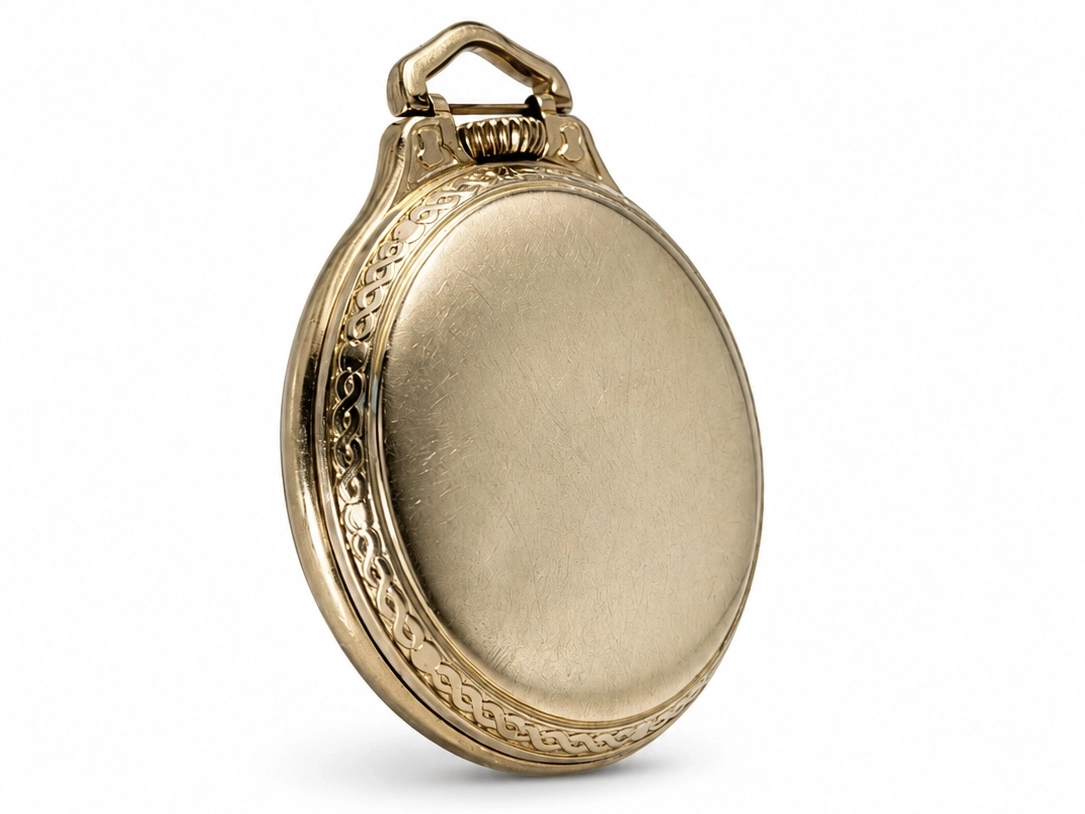 Gold pocket watch case back with decorative scrollwork border and smooth polished surface.