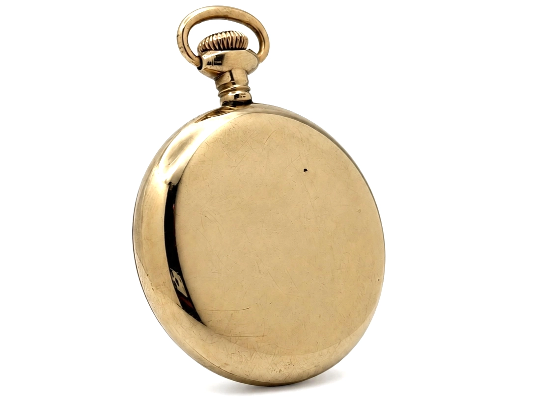 Closed gold-tone pocket watch case with loop bail and scratched surface patina.