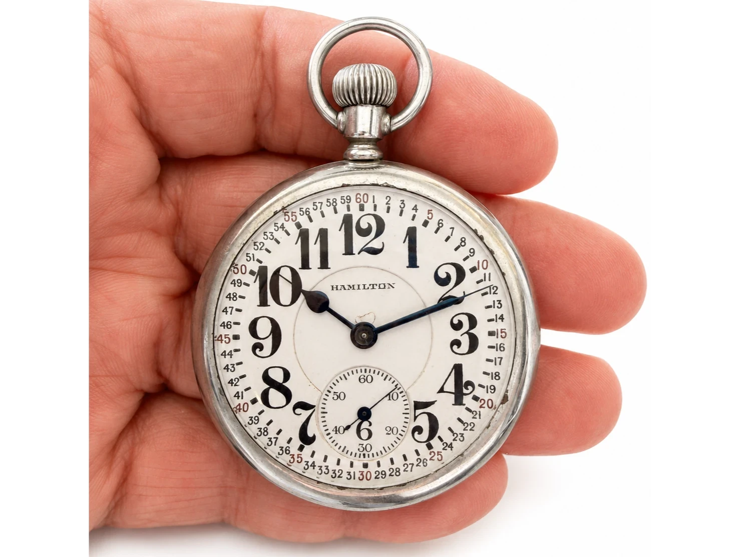 Hamilton pocket watch with Arabic numerals, subsidiary seconds dial, held in hand against white background.