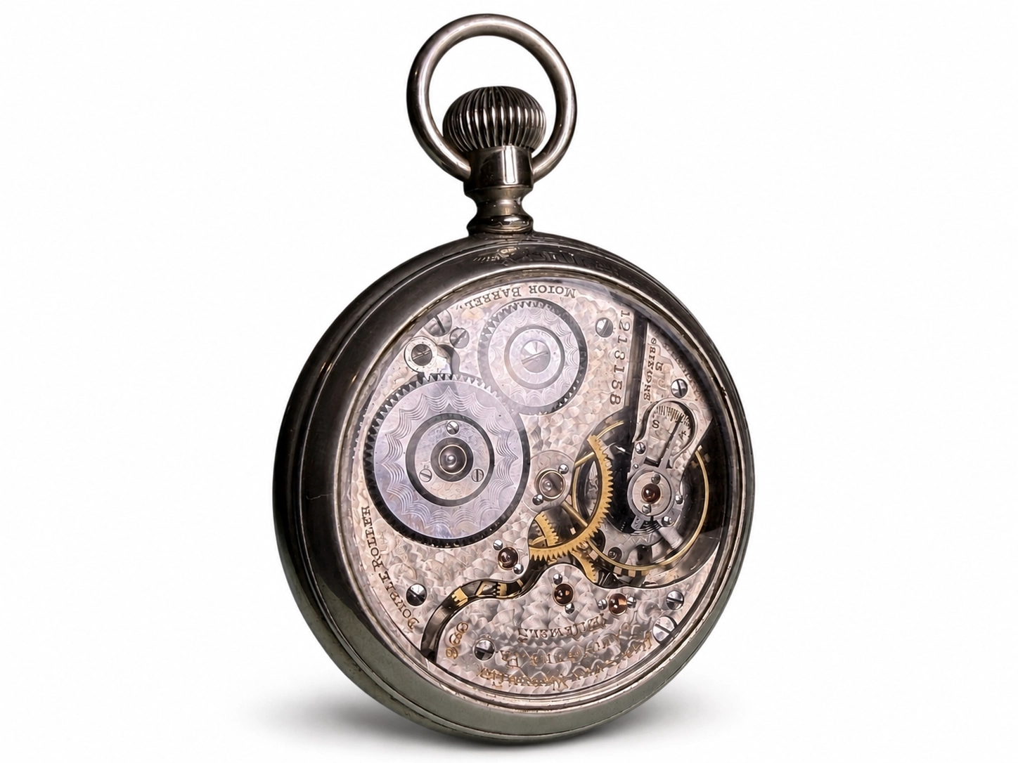 Open case view of pocket watch movement showing brass gears, jeweled escapement, and ornate damascening.