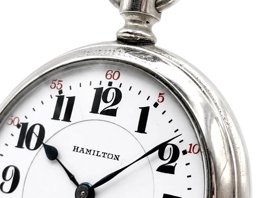 Hamilton pocket watch dial with Arabic numerals, blued steel hands, and white enamel face.