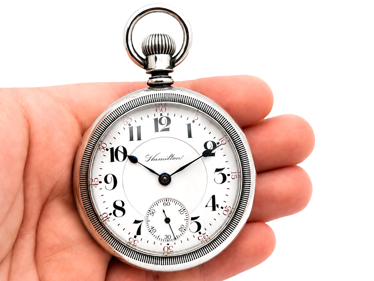 Open-face pocket watch with white dial, black Arabic numerals, center seconds hand, and subsidiary dial at 6 o'clock.
