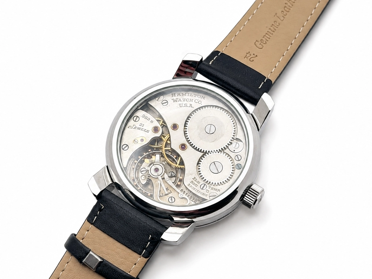 Hamilton open-face watch with visible movement, balance wheel, and gears on cream dial.