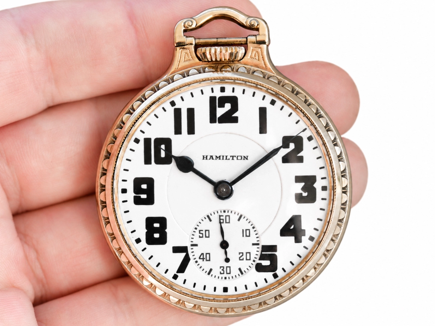 Open face pocket watch with white dial, bold Arabic numerals, subsidiary seconds dial, and gold-filled decorative case.