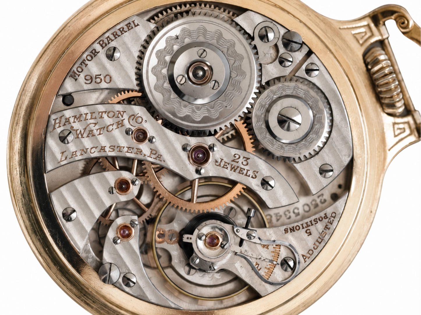 Open pocket watch movement showing decorated wheels, jewels, and Hamilton watch signature engraving.