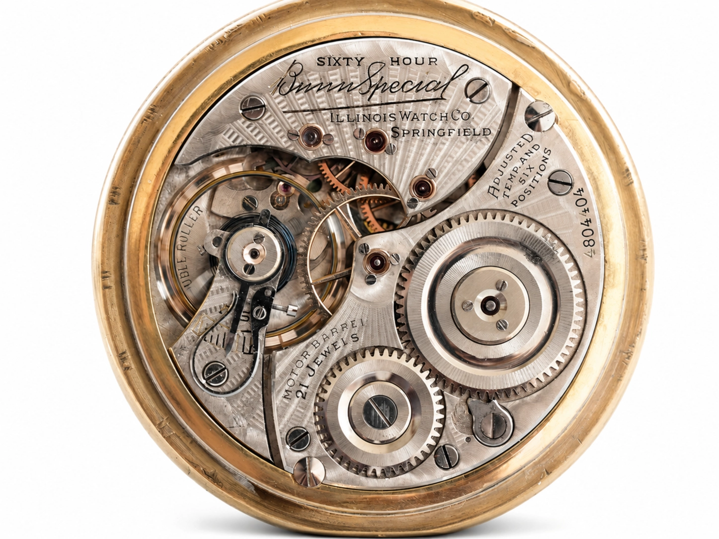 Open pocket watch movement showing jeweled gears, balance wheel, and Illinois Watch Co. dial engraving.