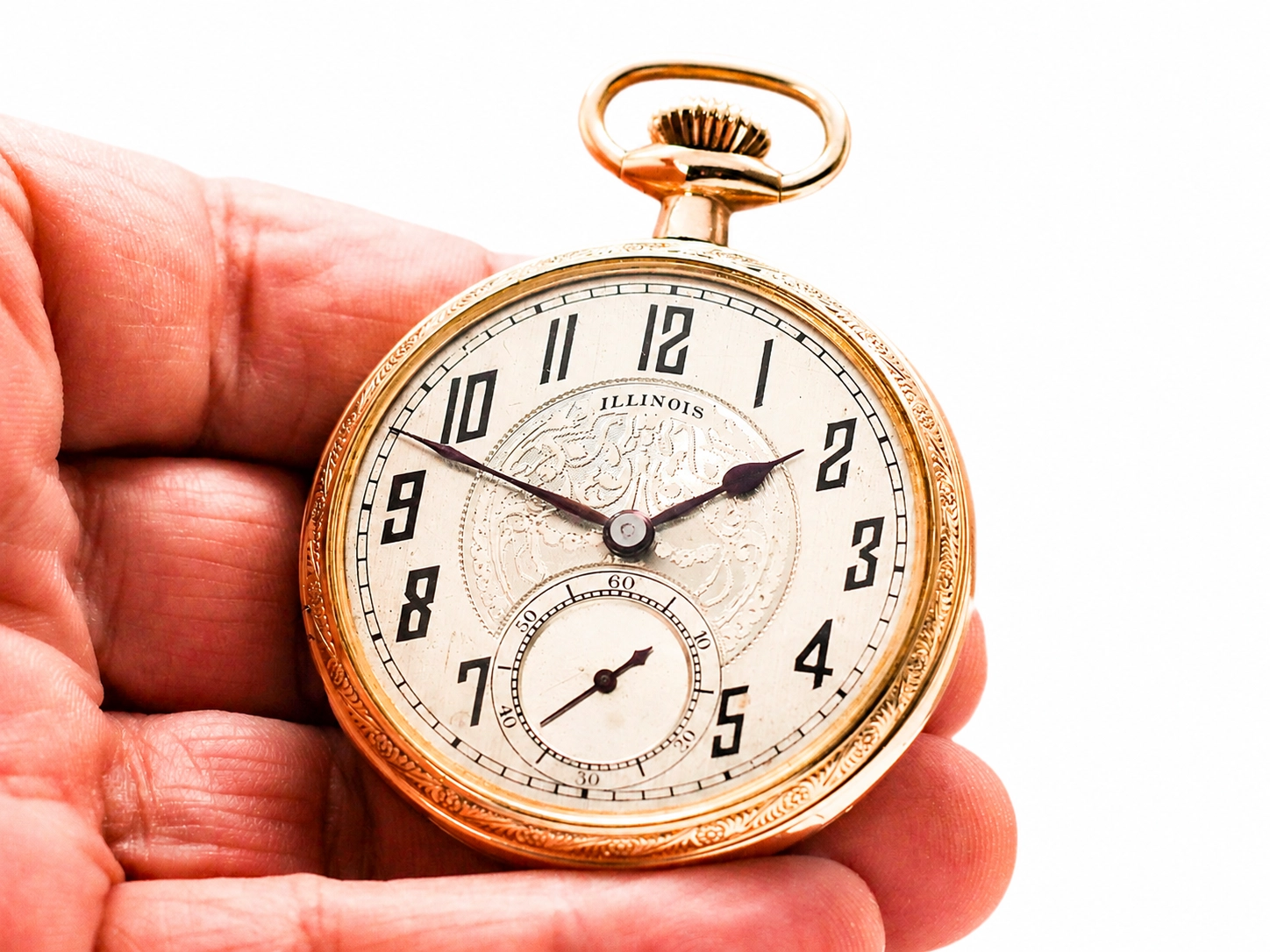 Gold Illinois pocket watch with Arabic numerals dial and subsidiary seconds subdial held in hand.