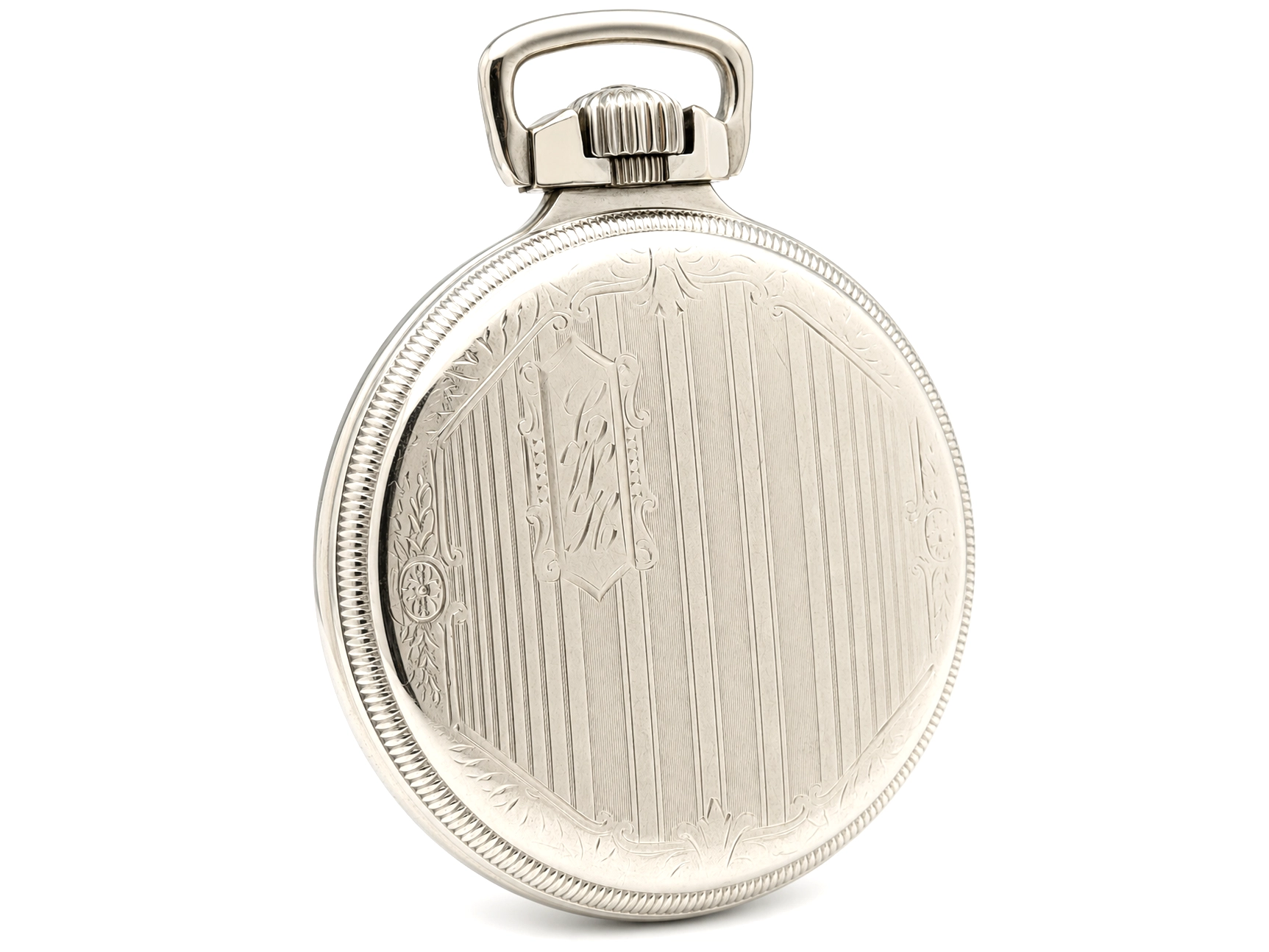 Polished metal pocket watch case back with engine-turned linear pattern and decorative border.