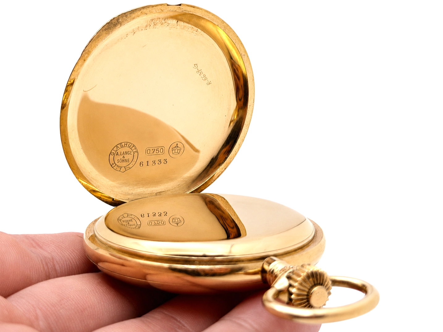 Open gold case showing interior hallmarks, 0.750 purity mark, serial 61333, and decorative shell-form bow.