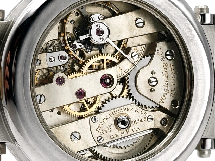Open movement view showing brass gears, jeweled bearings, and engraved plates with maker's mark.