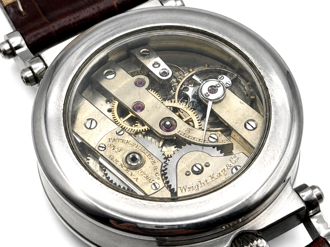 Open caseback revealing watch movement with jeweled components, brass plates, and visible gears.