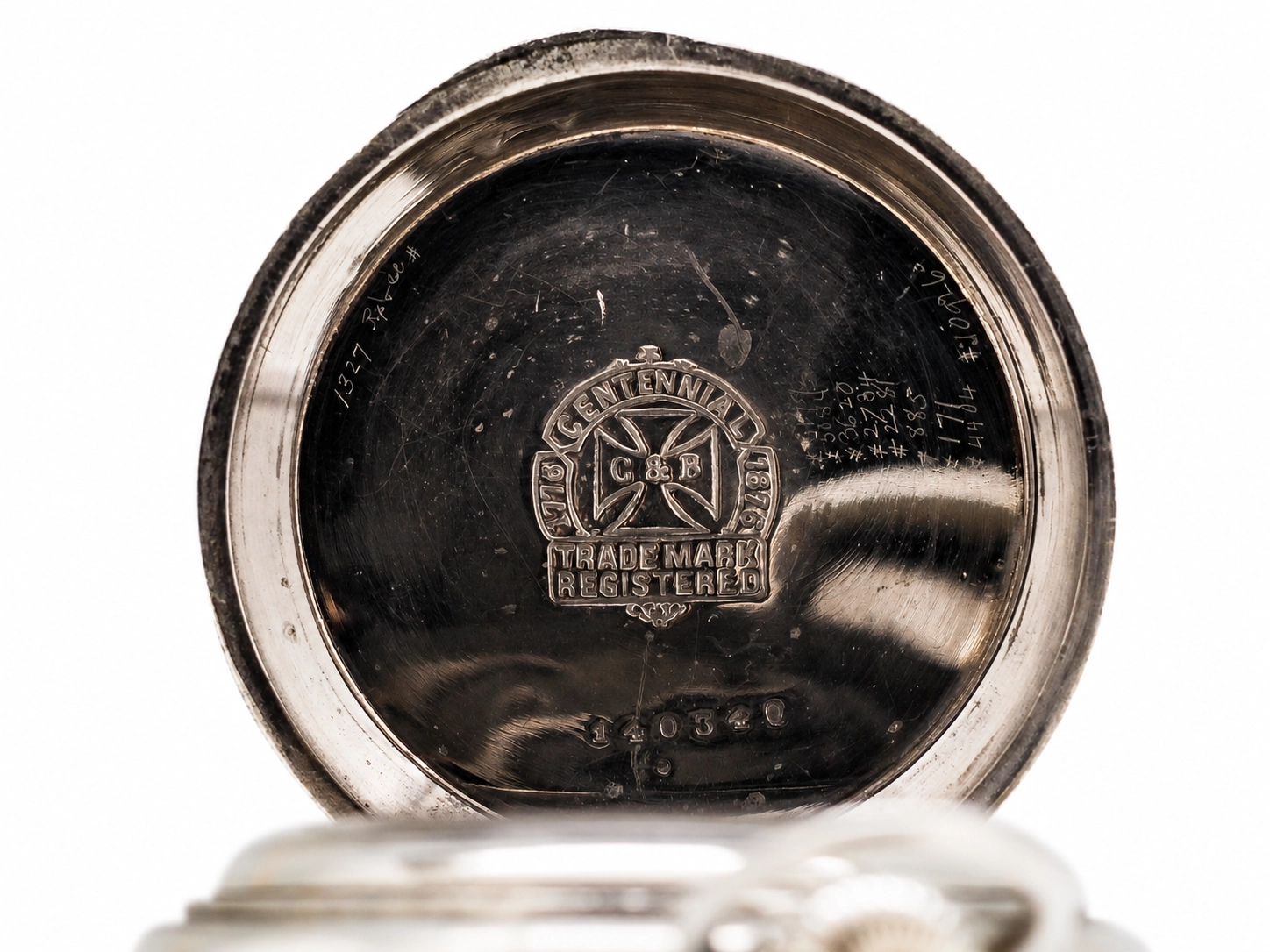 Metal case back with centennial trade mark emblem, hallmarks, and visible wear and patina.
