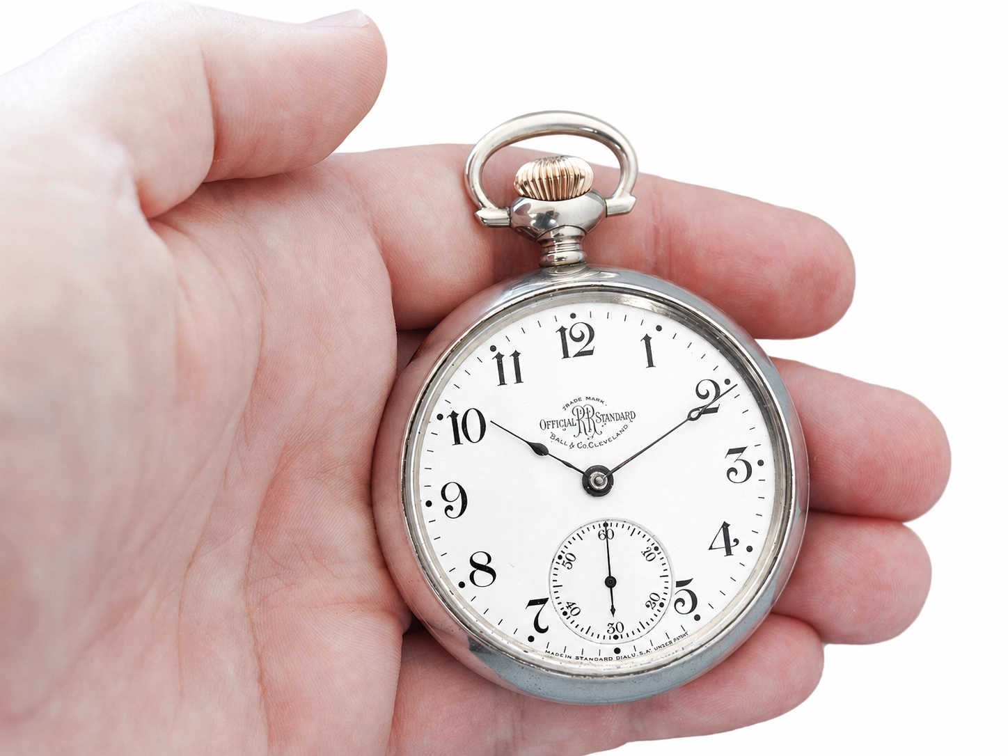 Silver pocket watch with white dial, Arabic numerals, subsidiary seconds dial, and polished case held in hand.