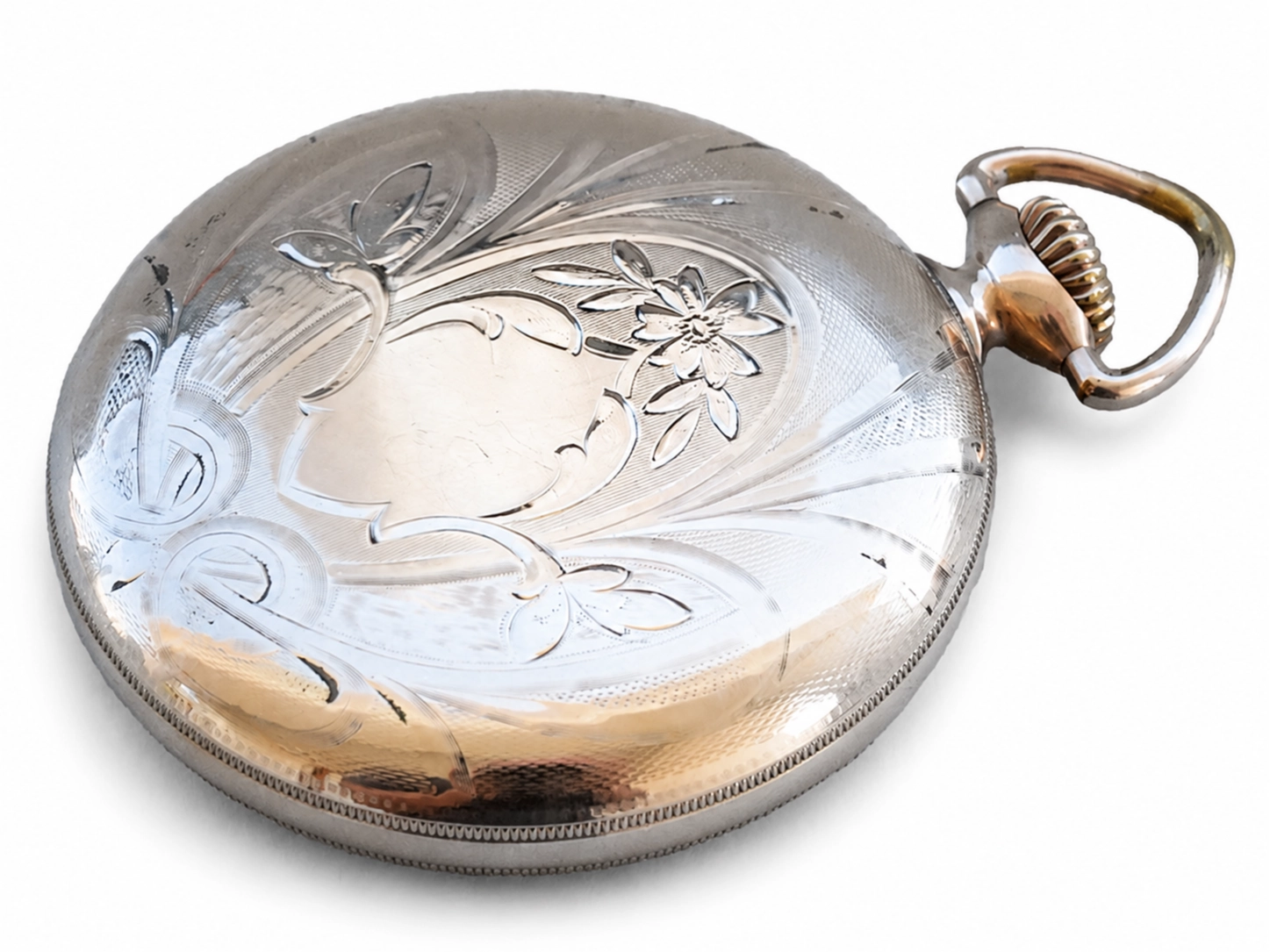 Polished metal case back with ornate floral engraving and gold-toned bow handle.