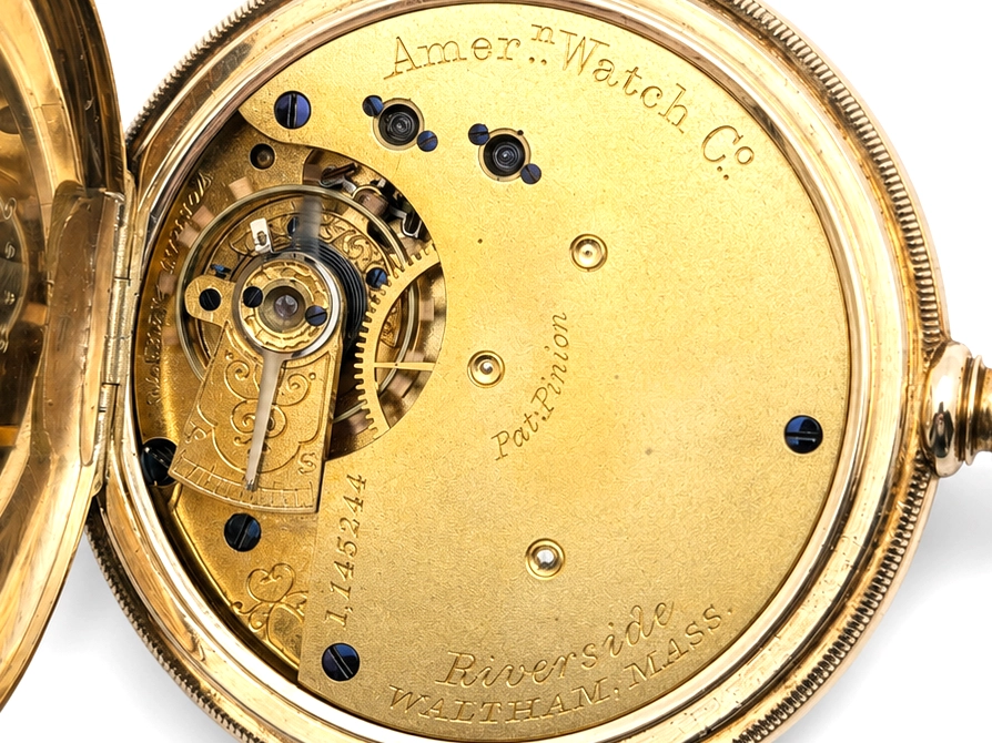 Open case back showing gold movement plate with blue jewels and "American Watch Co" engraving.