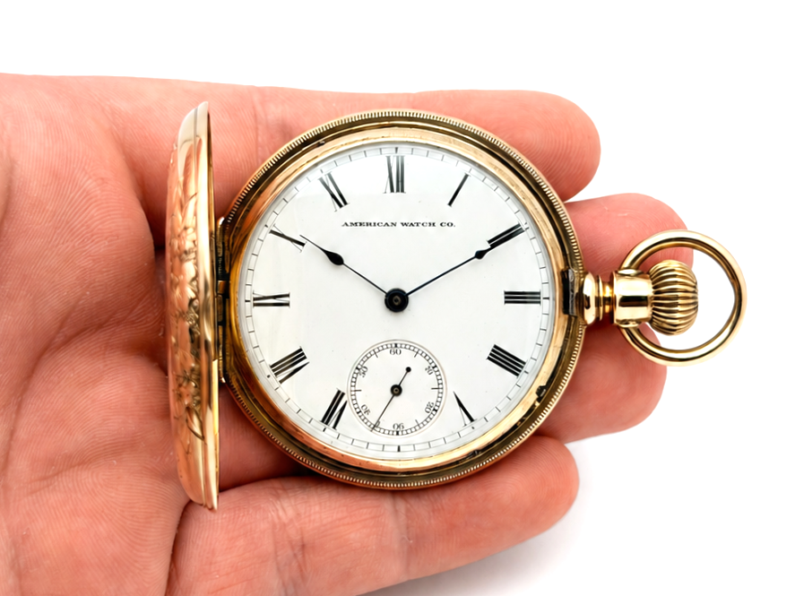Gold hunter case pocket watch with white dial, Roman numerals, and small seconds subdial, held in hand.