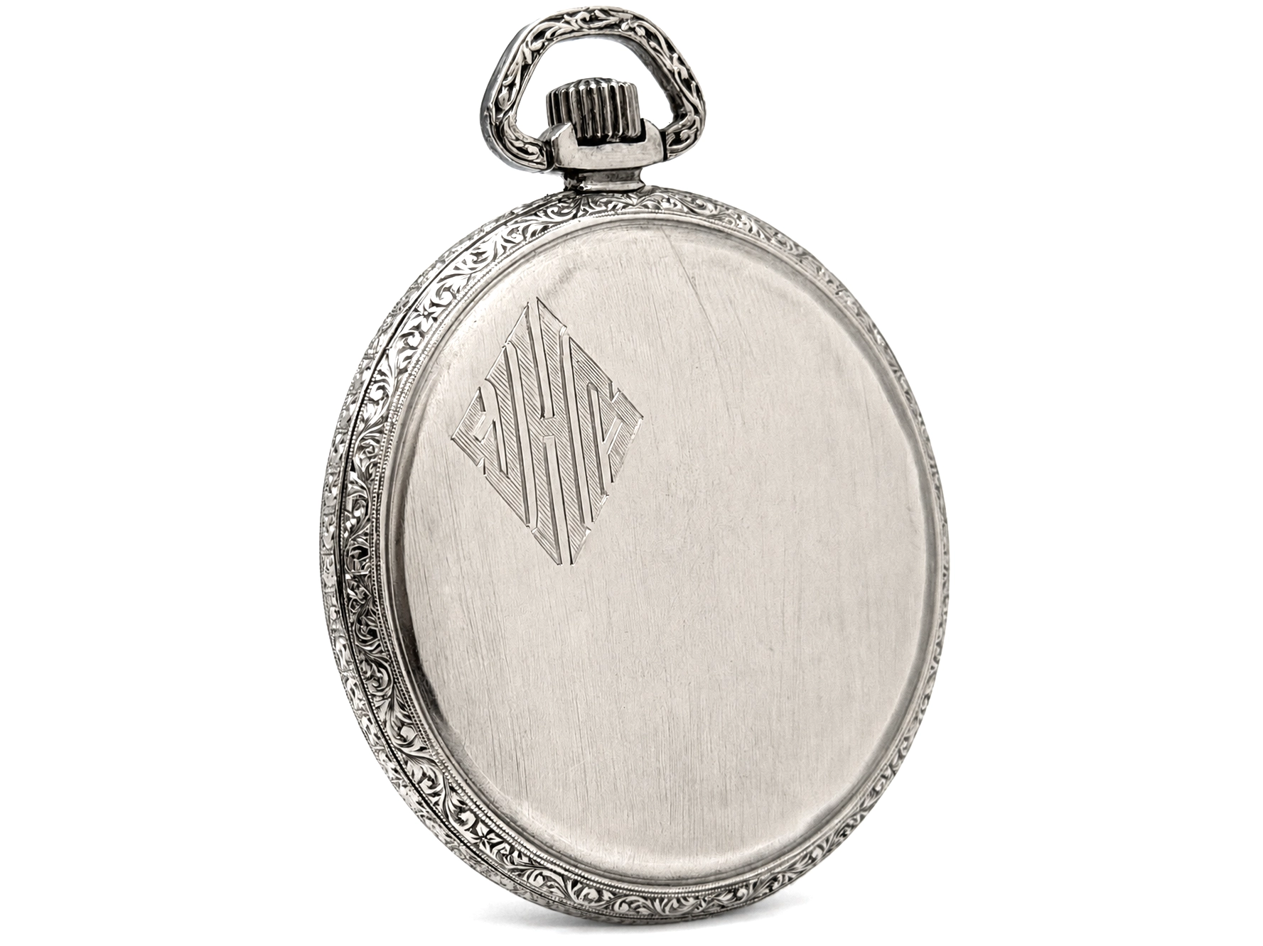 Silver pocket watch case back with ornate scrollwork border and engraved diamond monogram.