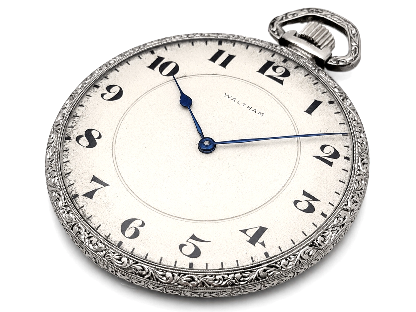 Waltham pocket watch with cream dial, black Arabic numerals, blue steel hands, and ornate silver case.