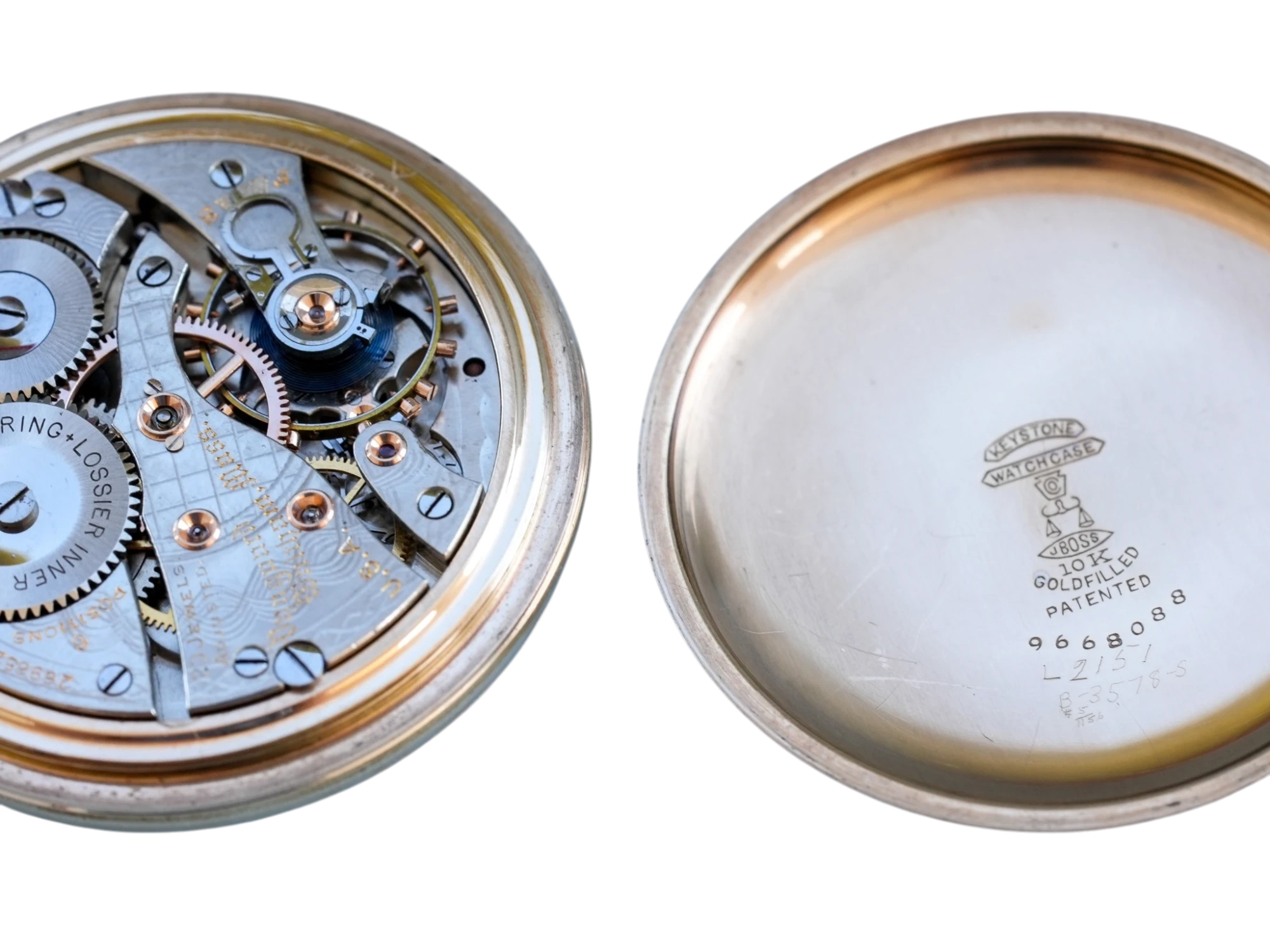 Open pocket watch movement showing jeweled escapement, gears, and gold-filled case back with Waltham patent markings.